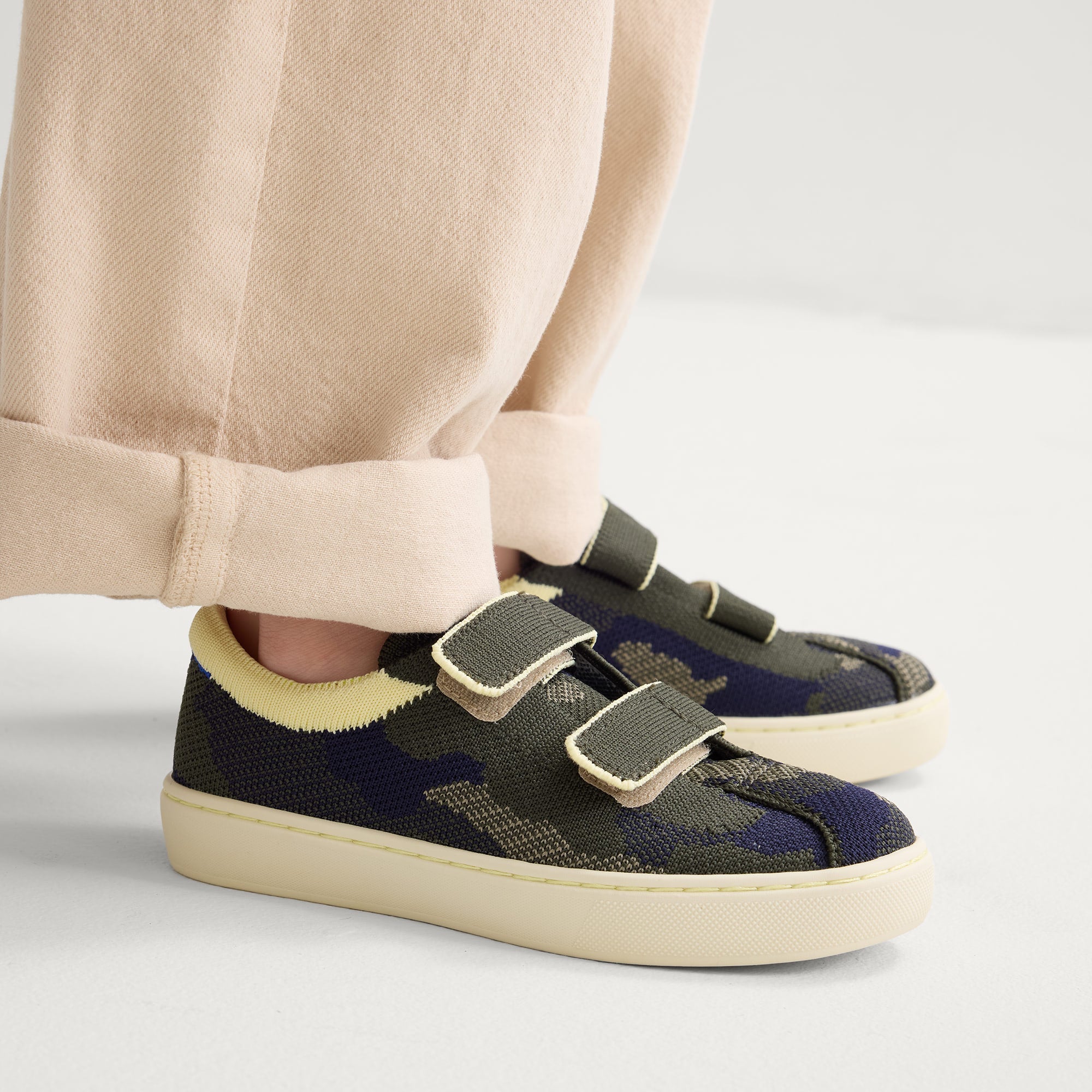hover | A child modeling The Kids Strap Sneaker in Spruce Camo. 