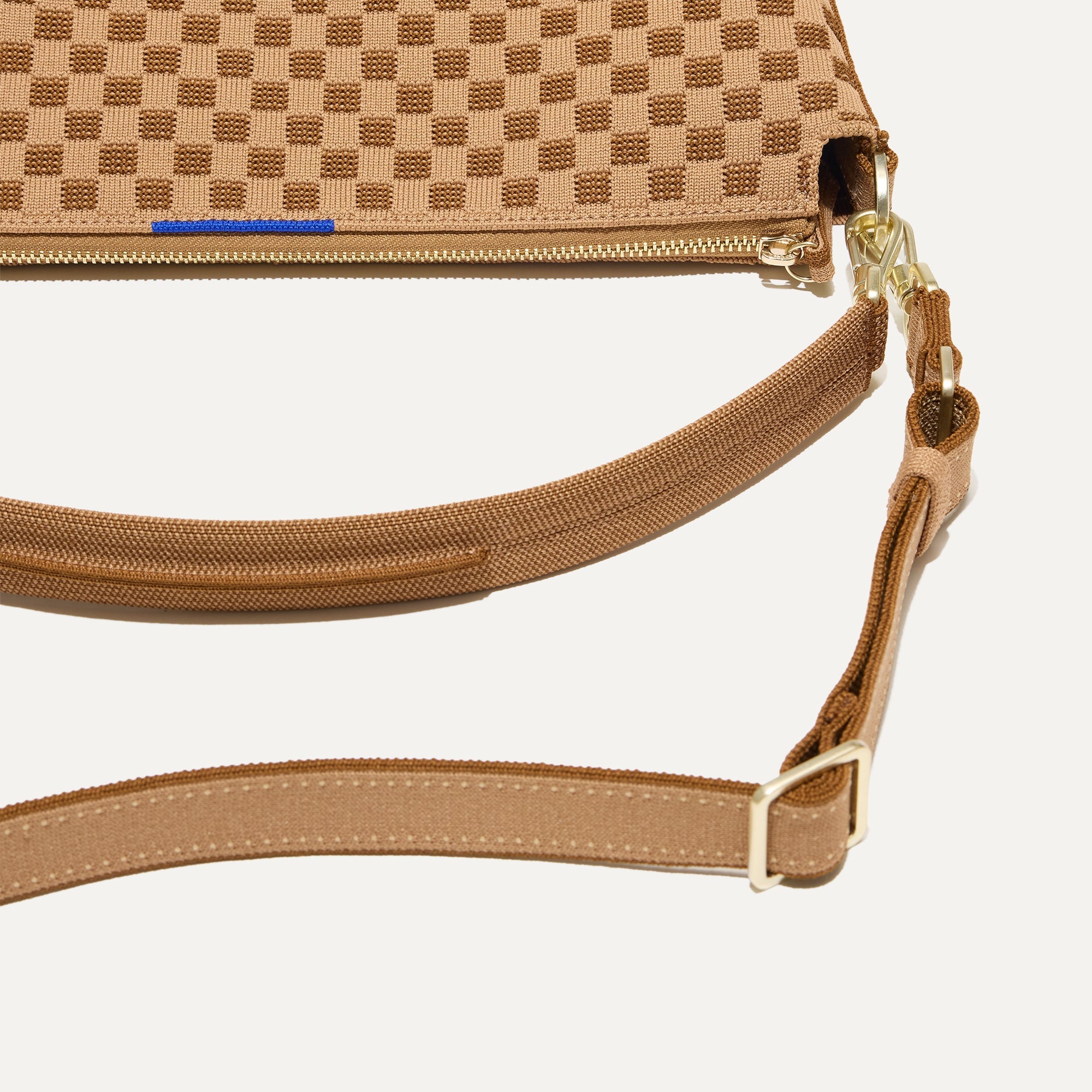 A closeup of The Daily Crossbody Bag in Hazelnut, showing the smooth zipper closure and soft, flexible handle.