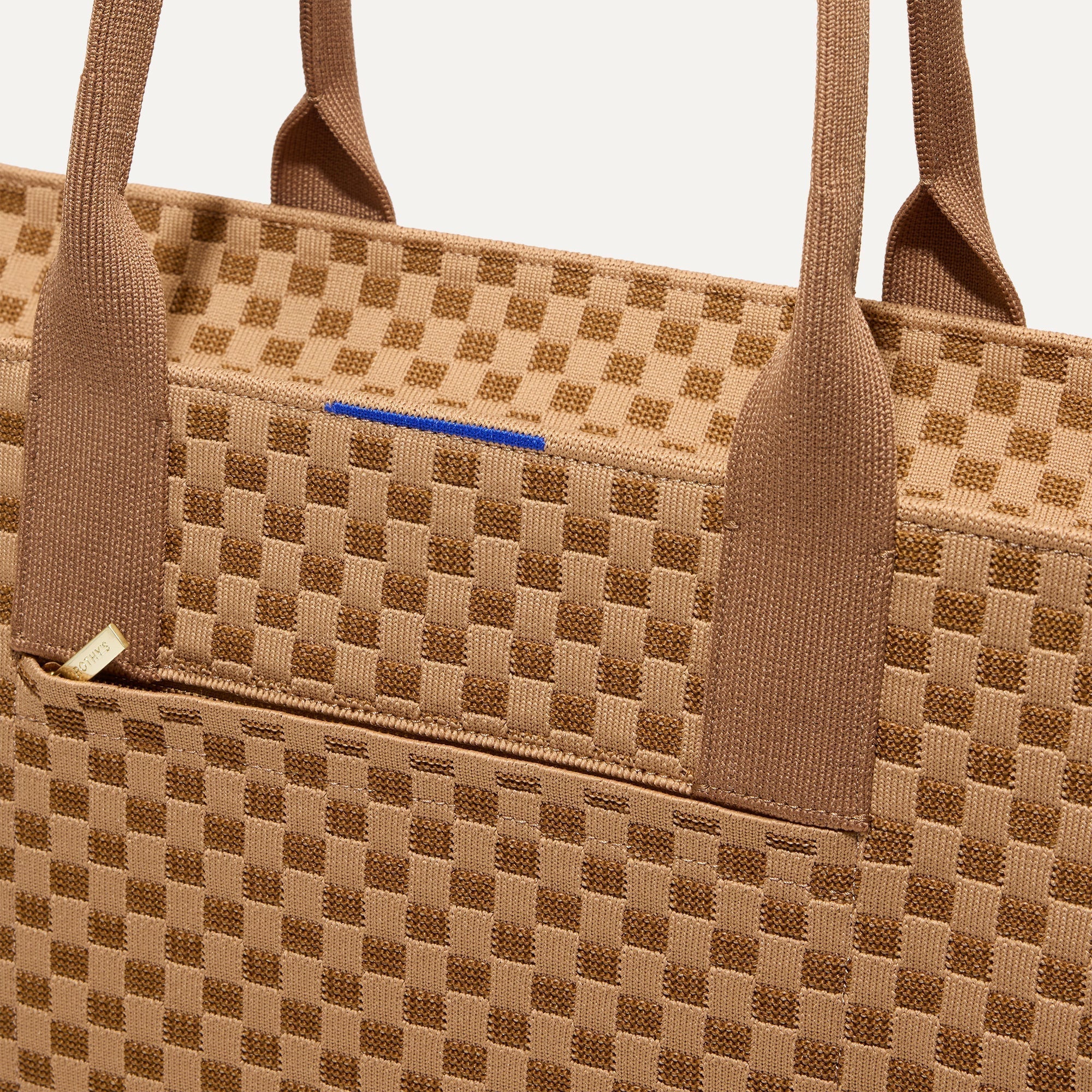 A closeup of The Classic Tote in Hazelnut, focusing on the exterior zip pocket. 