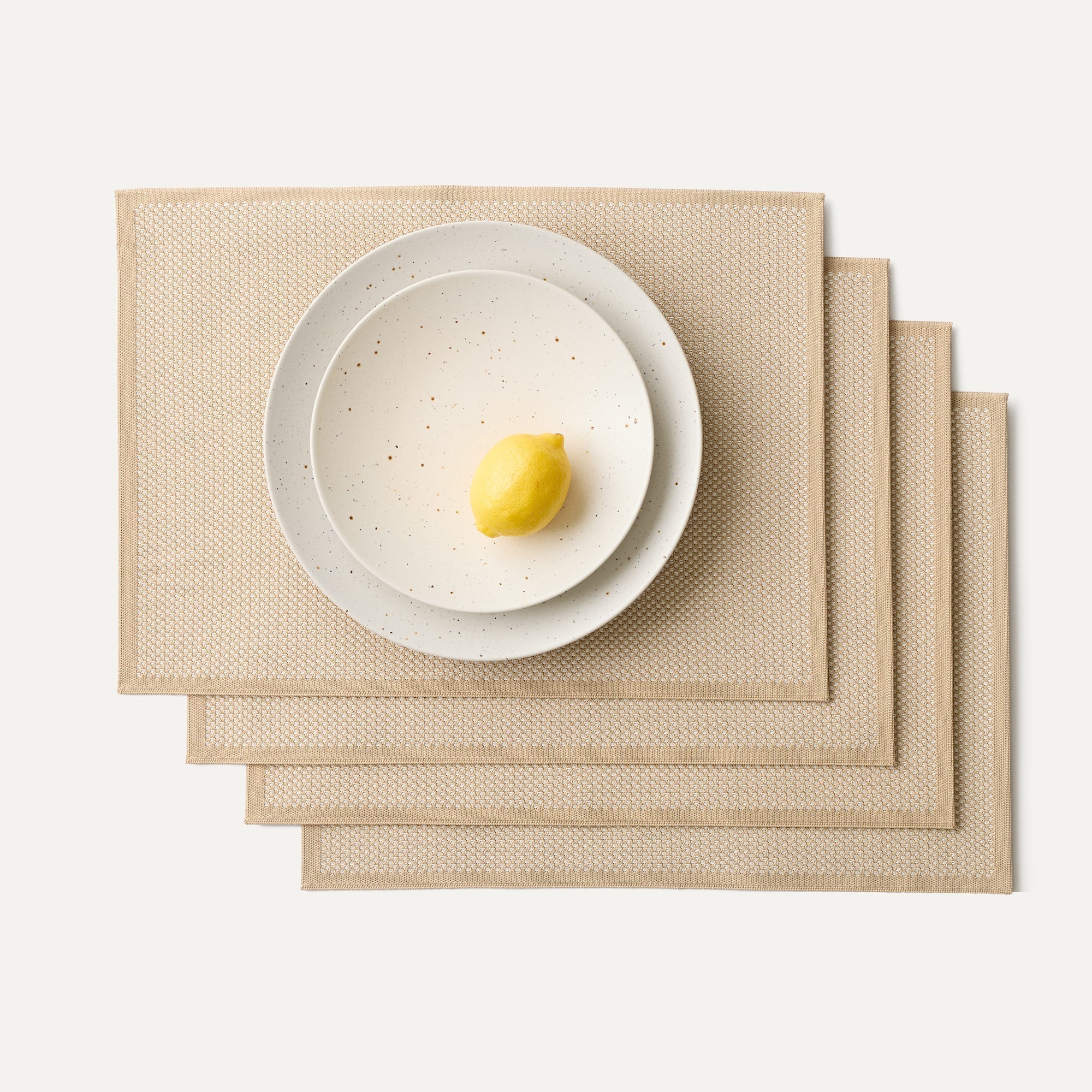 A set of four Placemats in Almond shown with a plate setting.