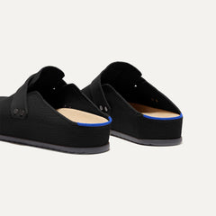 Close up of the heel of The Men's Clog in Soft Black, with Rothy's signature blue halo. 