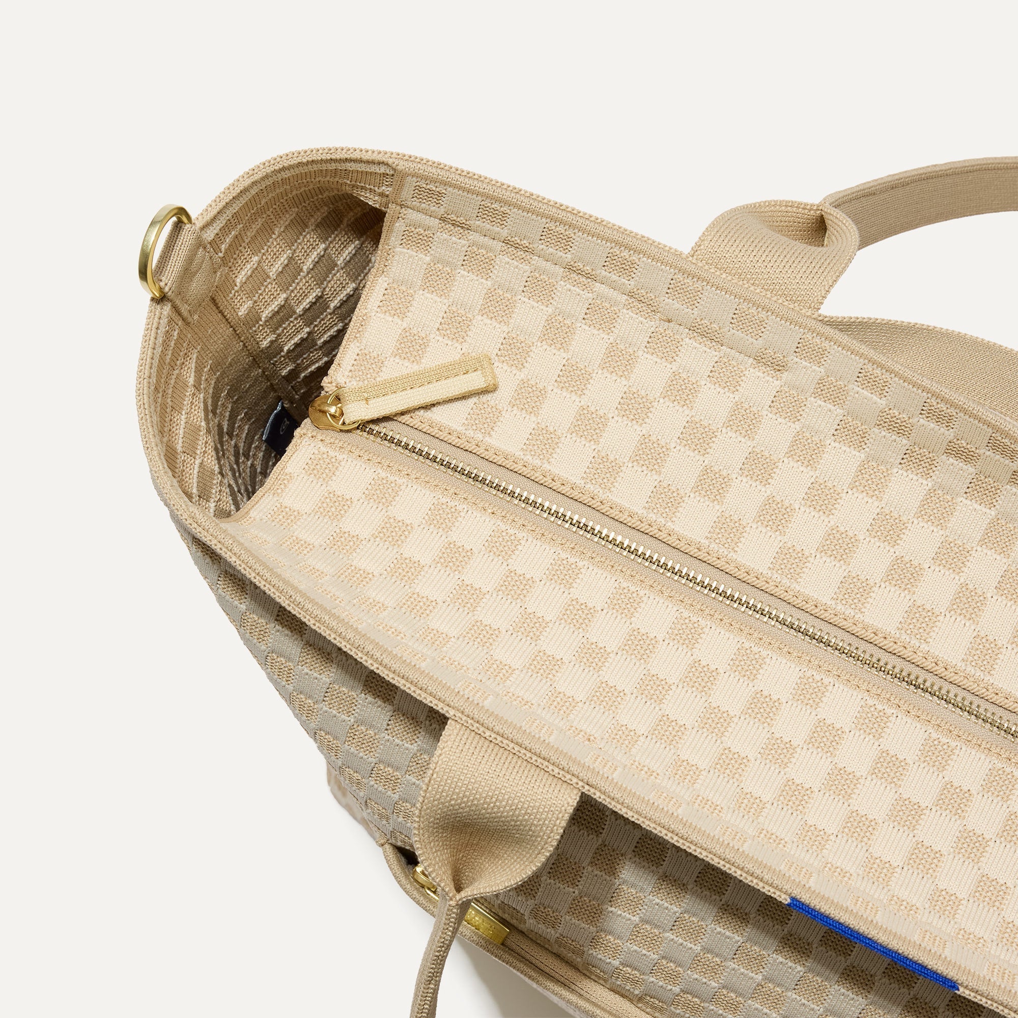 A close up of The Zip Travel Tote in  Parchment Basketweave, focusing on the zip closure and handles.