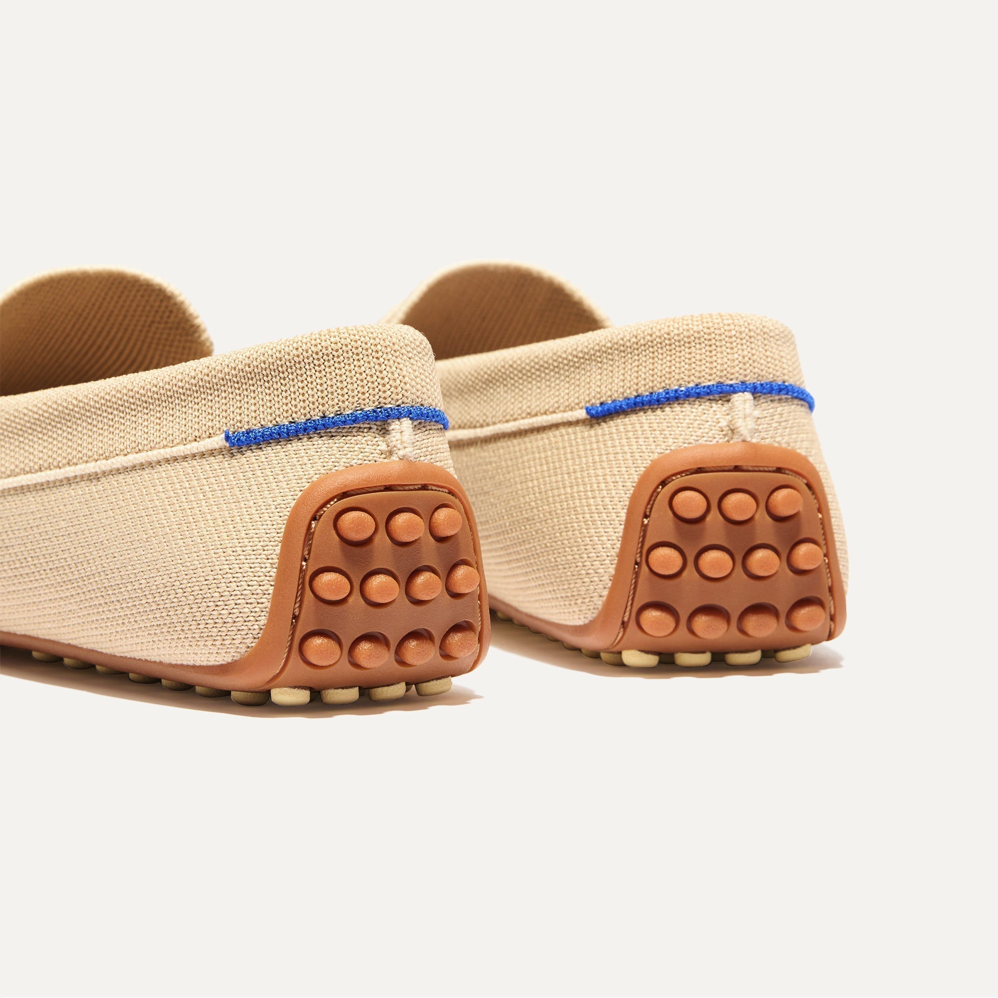 Close up of the heel of The Daily Driver in Sesame, with raised peg outsoles and Rothy's signature blue halo. 