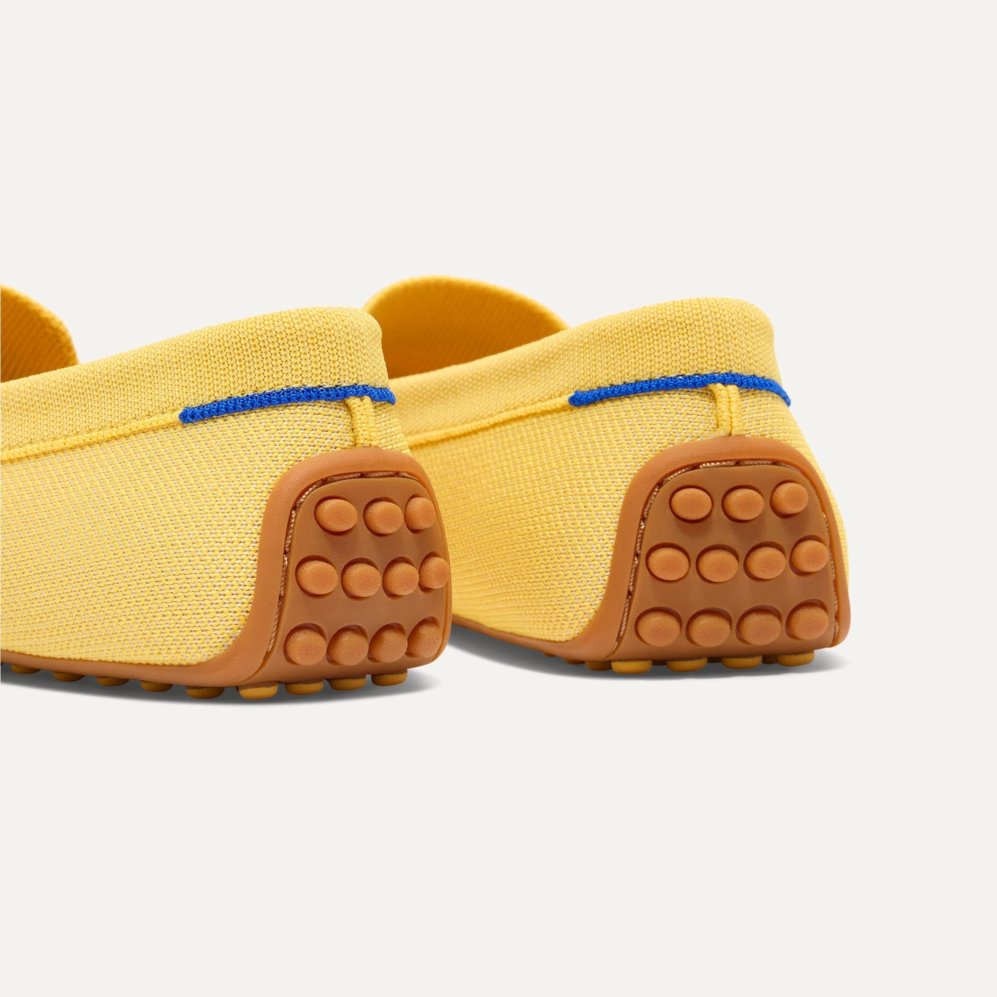 Close up of the heel of The Daily Driver in Sunwashed Yellow, with raised peg outsoles and Rothy's signature blue halo. 