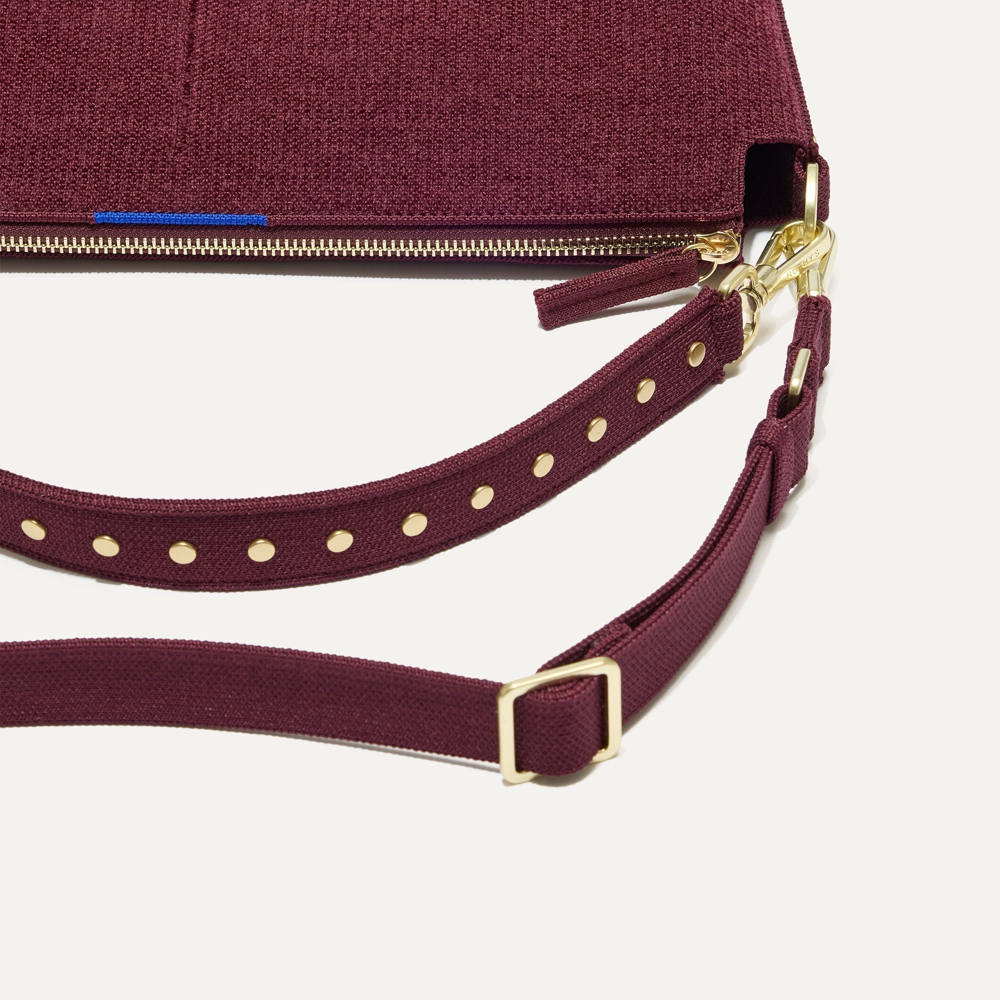 The Daily Crossbody in ReVelvet™ Syrah, lying flat, showing the detachable top handle and adjustable crossbody strap.